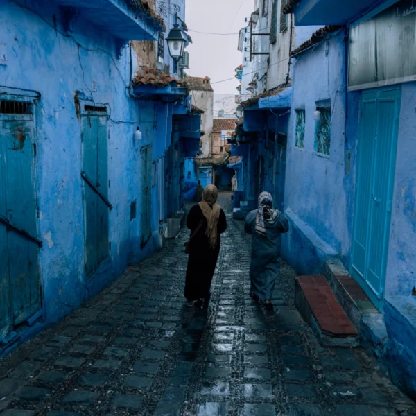 Two women walking a blue cobbled street in the Chefchaouen medina